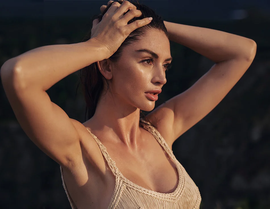 Woman with wet hair, standing outdoors in the evening light, looking intently into the distance - Facial Fat Grafting in Houston, TX