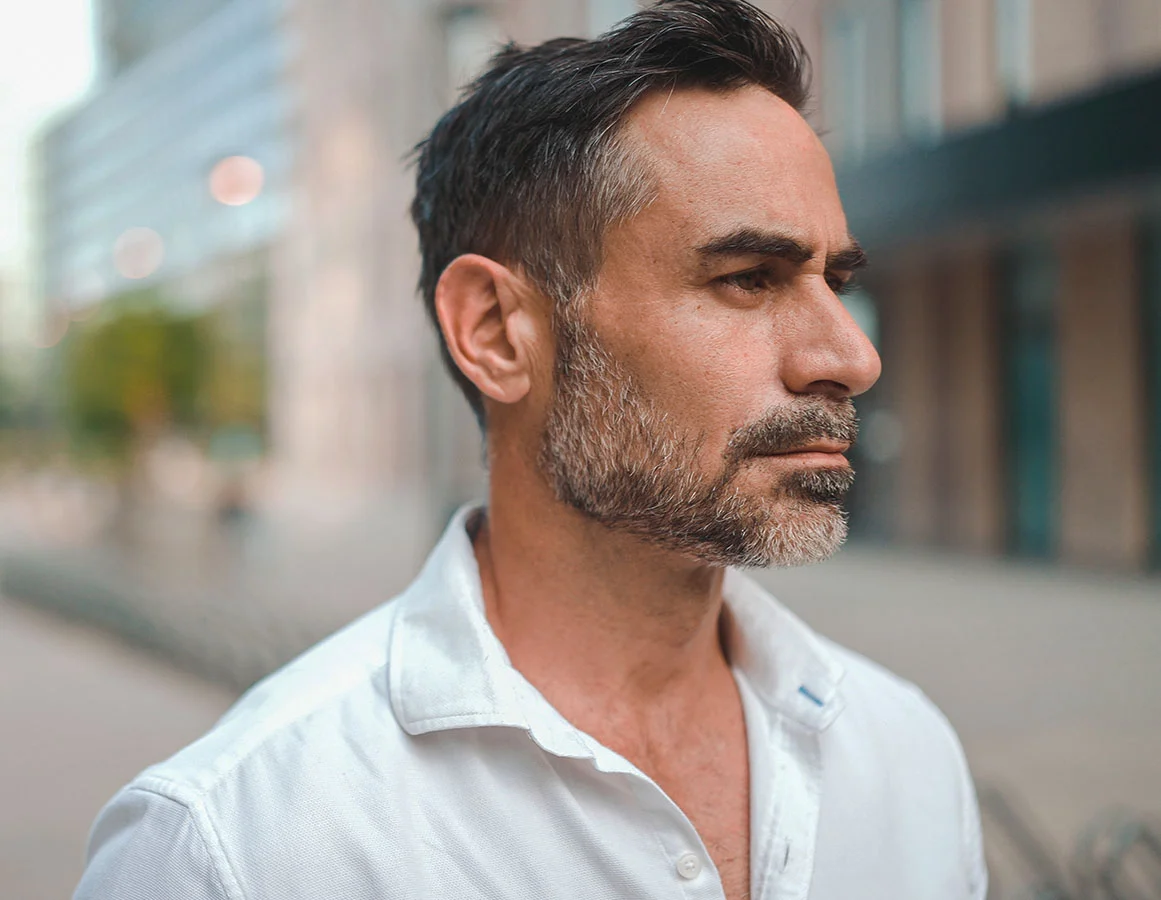 A man with a salt and pepper beard, walking in an urban area - Facelift in Houston Texas